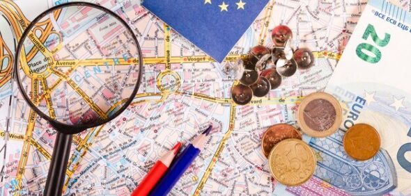 Euro currencies with magnifying glass pushpins pencils flag world map 23 2147837098